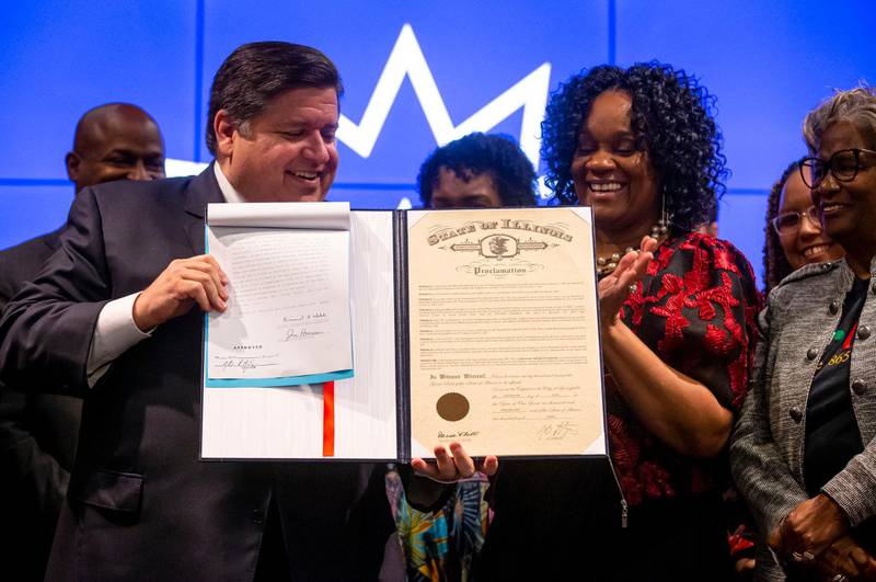 Illinois Gov. JB Pritzker and Illinois State Sen. Kimberly Lightford, D-Maywood, hold up the bill marking Juneteenth an official state holiday in Illinois during a bill signing at the Abraham Lincoln Presidential Library in Springfield, Ill., Wednesday, June 16, 2021.  (Justin L. Fowler/The State Journal-Register via AP)