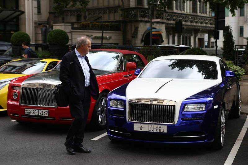A man walks past a Saudi Arabian-registered and a Kuwaiti-registered Rolls-Royce. Carl Court / Getty Images
