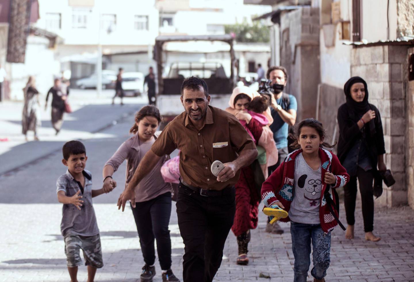 People run to take cover after mortars fired from Syria, in Akcakale, Turkey, Thursday, Oct. 10, 2019. An Associated Press journalist said at least two government buildings were hit by the mortars in Sanliurfa province's border town of Akcakale and at least two people were wounded. (Ismail Coskun/IHA via AP )