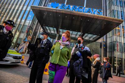 Police officers detain an activist from the Extinction Rebellion, a global environmental movement, outside the Barclays offices in Canary Wharf, London, Britain, April 7, 2021. REUTERS/Toby Melville