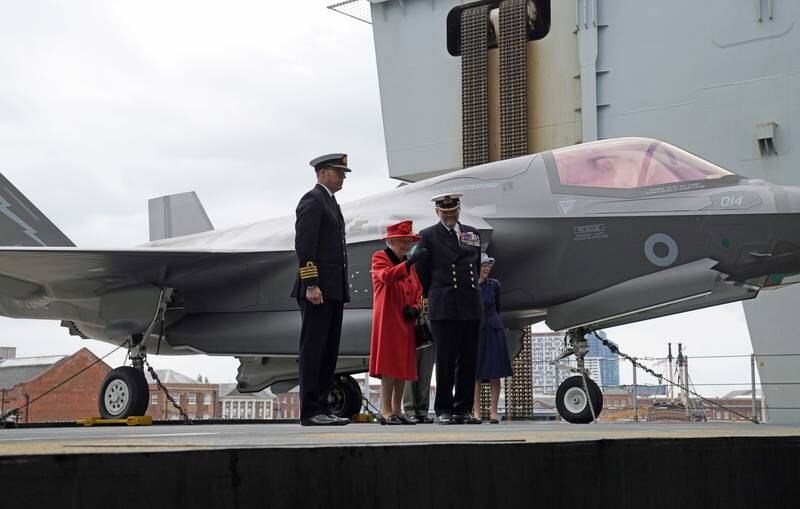 Capt Angus Essenhigh, Queen Elizabeth and Commodore Steve Moorhouse during a visit to 'HMS Queen Elizabeth' before the ship's maiden deployment in May in Portsmouth.