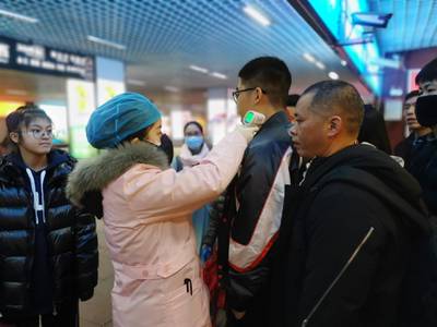 A medical staff member checks the body temperature of passengers as they arrive at a railway station in Yingtan City, Jiangxi province, China. EPA
