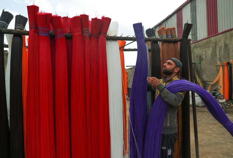 A factory worker arranges fabric for carpet weaving.