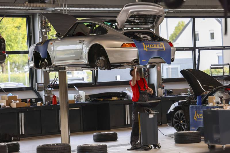 An employee works on a Porsche 911 at a dealership in Dortmund, Germany. Bloomberg