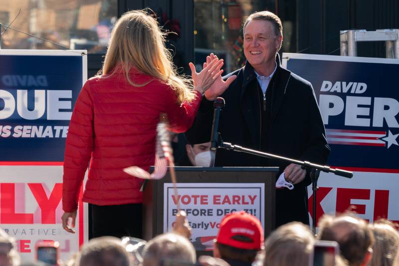 Senators Kelly Loeffler and David Perdue  high five each other as Mr Perdue takes the stage to speak during a campaign event in Milton, Georgia. AFP
