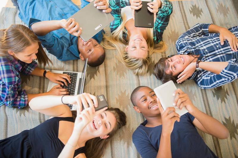 Teenagers laying on floor using technology. Getty Images