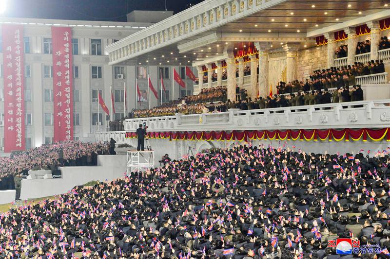 People wave the national flags as North Korean leader Kim Jong-un, centre top, attends a military parade, at Kim Il-sung Square. KCNA / AP