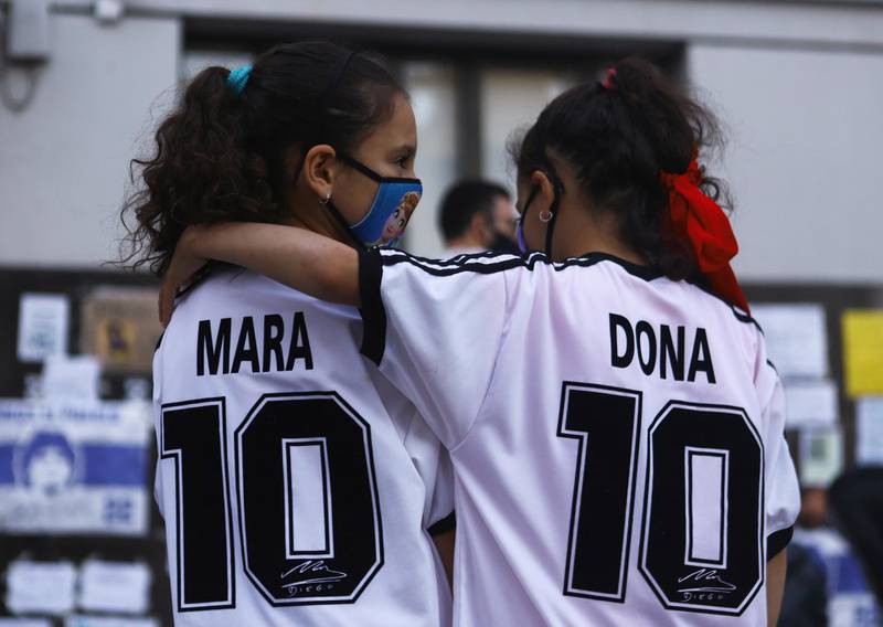 Twin sisters Mara and Dona Rotundo, named after Diego Maradona, embrace outside the clinic. Reuters