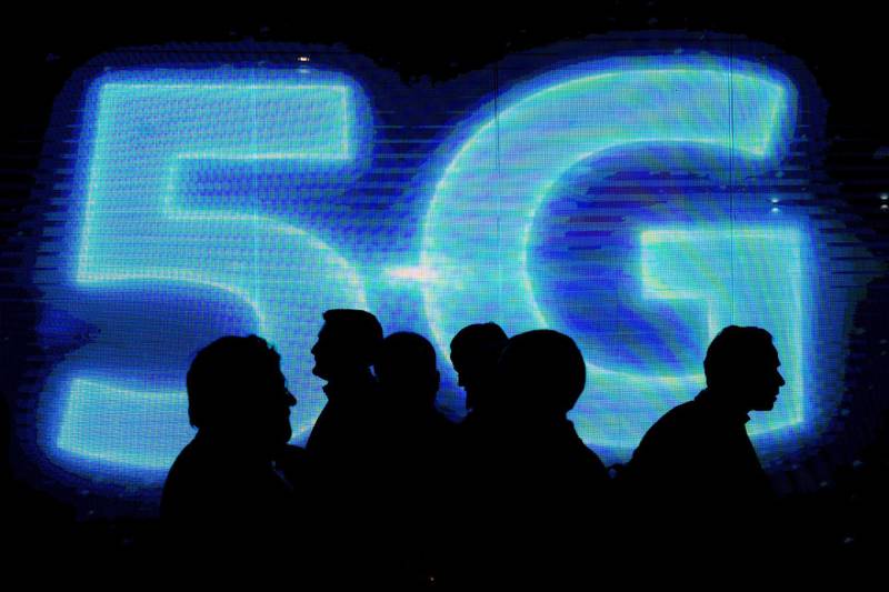 Visitors walk past a 5G logo during the Mobile World Congress on the third day of the MWC in Barcelona, on March 1, 2017. - Phone makers will seek to seduce new buyers with artificial intelligence functions and other innovations at the world's biggest mobile fair starting today in Spain. (Photo by Josep Lago / AFP)