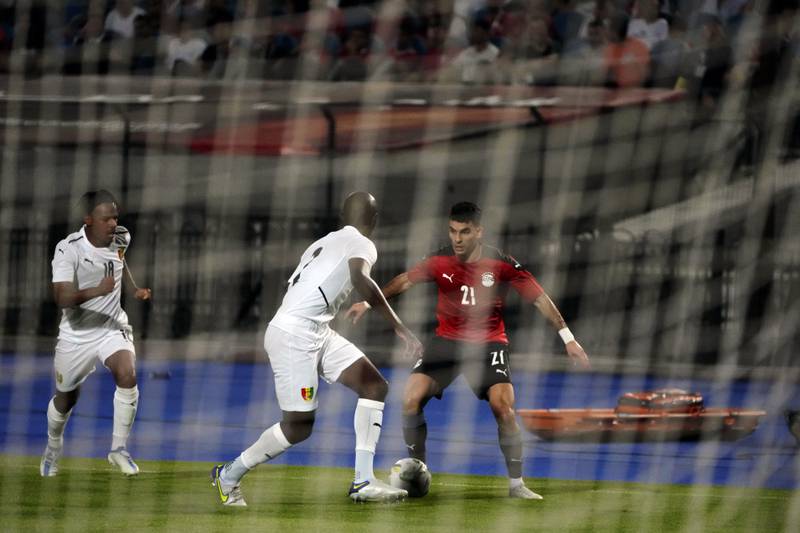 Egypt's Zizo, right, and Guinea's Conte are seen through the goal net during their soccer match in Group D 2023 Cup of Nations (AFCON) qualifiers at Cairo International stadium in Cairo, Egypt.  Egypt won 1-0. AP Photo