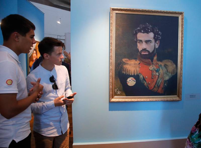 Visitors look at a portrait of Egypt's Mohamed Salah, part of the "Like The Gods" exhibition, at the Museum of the Russian Academy of Arts in St. Petersburg, Russia. Dmitri Lovetsky / AP Photo