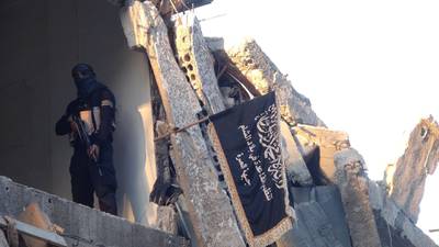 A fighter from the al-Qaida group in the Levant, Al-Nusra Front,  poses  next to the movements flag in a destroyed building near the front line with Syrian government solders in  Yarmuk Palestinian refugee camp, south of Damascus on September 22, 2014. The Syrian Observatory for Human Rights says more than 180,000 people have been killed in the Syrian conflict since it erupted in March 2011, while the United Nations puts the figure at 191,000. AFP PHOTO/ RAMI AL-SAYED (Photo by RAMI AL-SAYED / AFP)