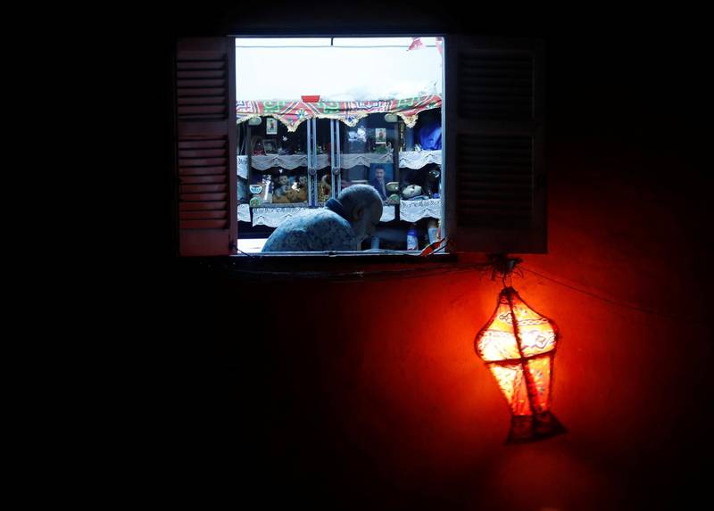 A man reads the Koran, seen from a window of his house decorated with a traditional Ramadan lantern called "fanous", on the Laylat al-Qadr, or Night of Power, the holiest night for Muslims, during a night-time curfew amid the spread of the coronavirus disease (COVID-19) in Cairo, Egypt. REUTERS