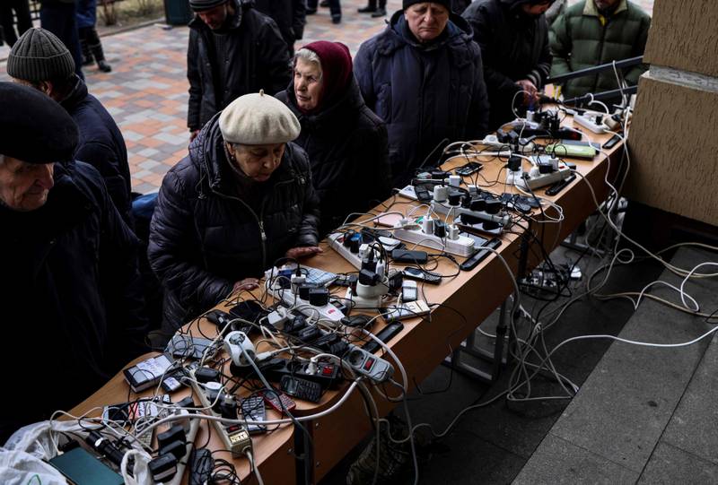 People charge their mobile phones in a public building in Bucha. AFP
