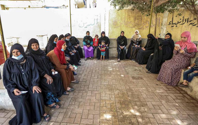 Woman voters, some mask-clad due to the Covid-19 coronavirus pandemic, wait before entering a polling station in El Ayyat, south of the Egyptian capital, during the first stage of the lower house elections. AFP