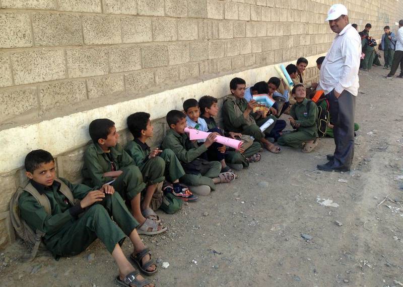 Yemeni children sit outside a school controlled by Houthi rebels. AFP 