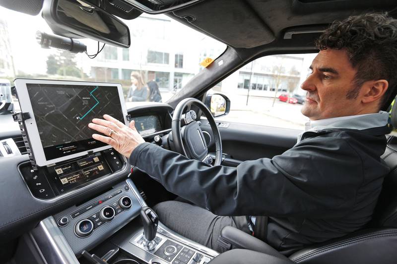 Safety driver Jim O'Donoghue shows the route on a screen of a self driving Range Rover during a demonstration of connected and autonomous cars that will park, emergency brake and show other emergency vehicle and warning features for the first time on open public roads in Milton Keynes, England, Thursday, March 22, 2018. (AP Photo/Frank Augstein)