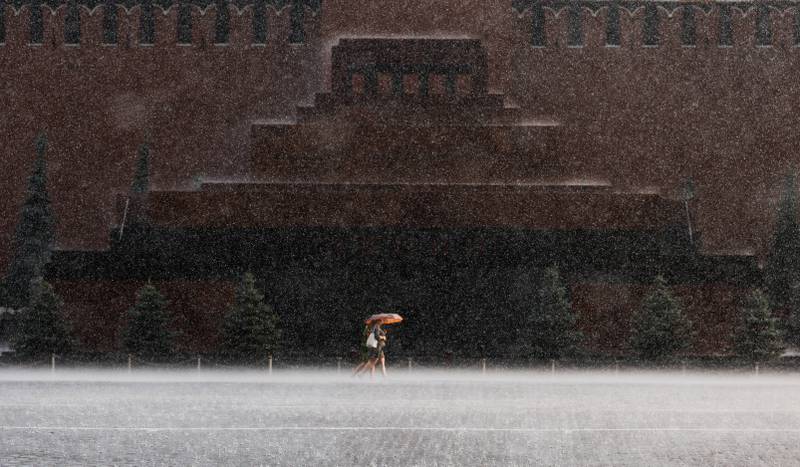 People walk by Lenin's Mausoleum during heavy rain in Red Square, Moscow. Reuters