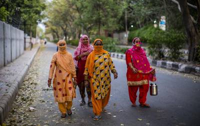 Indian women carry containers to buy milk as they walk on a deserted road amid a nationwide lockdown, in New Delhi, India. Getty Images