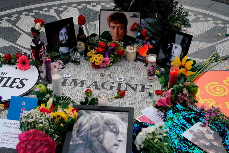 Picturs are seen on a monument as mourners gather on the 40th anniversary of John Lennon's death, at Strawberry Fields, in Central Park to honor the late Beatles star in New York on December 8, 2020.  / AFP / TIMOTHY A. CLARY
