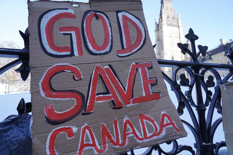 A sign reads 'God Save Canada' on the fence surrounding Canada's Parliament building. Willy Lowry / The National