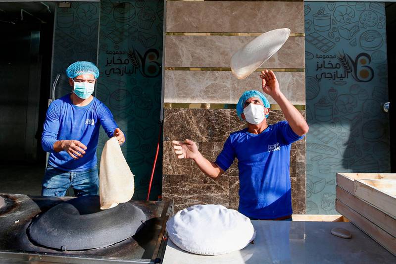 A baker wearing a protective mask and hairnet tosses dough in the air while preparing traditional bread at a bakery in Gaza City.  AFP