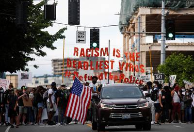 A protester sits out of the window of a car with an American flag as a youth-led protest walks towards the Seattle Police Department's West Precinct in Seattle. Reuters