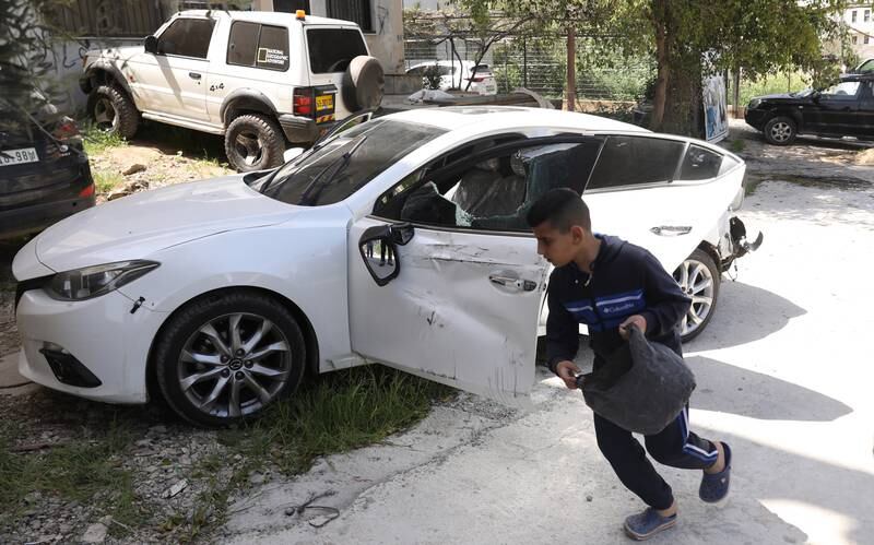 A child recovers items from the car of Ahmed Al Sadi, who was killed during clashes that erupted after Israeli troops raided the refugee camp, near Jenin. EPA