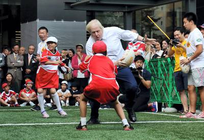 London Mayor Boris Johnson (C) plays rugby with Japanese elementary school children in Tokyo on October 15, 2015 during a promotional event for the 2019 Rugby World Cup which will be held in Japan. AFP PHOTO (Photo by STR / AFP)