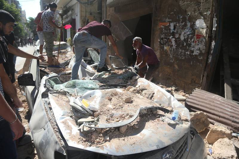 Lebanese men clears rubble, one day after the explosion at the Beirut Port, in the Gemayzeh area.  EPA