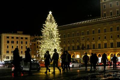 People walk by the Christmas tree that was placed in Piazza Venezia (Venice Square), downtown Rome.  AP