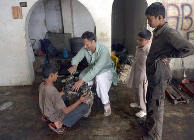 Blind Pakistani mechanic Asif Patel, second from left,  working on a car engine at his workshop in Karachi. Mr Patel's story is a rare tale of success in a country which offers few opportunities for the blind. Rizwan Tabassum/AFP Photo