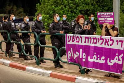 Israeli policemen gather next to a protester holding up a sign reading in Arabic and Hebrew "police racism kills" and behind a banner reading in Arabic "enough violence and criminality", during a protest against the government's insufficient action towards rising violence levels within the Arab community, outside the home of Public Security Minister Omer Bar-Lev in the northern Israeli town of Kokhav Yair. AFP
