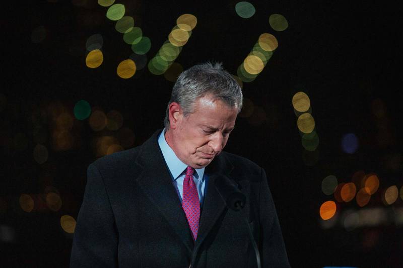 New York's Mayor Bill de Blasio takes a moment of silence as images of Covid-19 Victims are projected over the Brooklyn bridge as the city commemorates a Covid-19 Day of Remembrance in Brooklyn, New York on March 14, 2021. / AFP / POOL / Kevin Hagen
