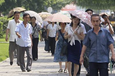 Pedestrians under parasols in Mirae Scientist Street in Pyongyang, North Korea. AP 