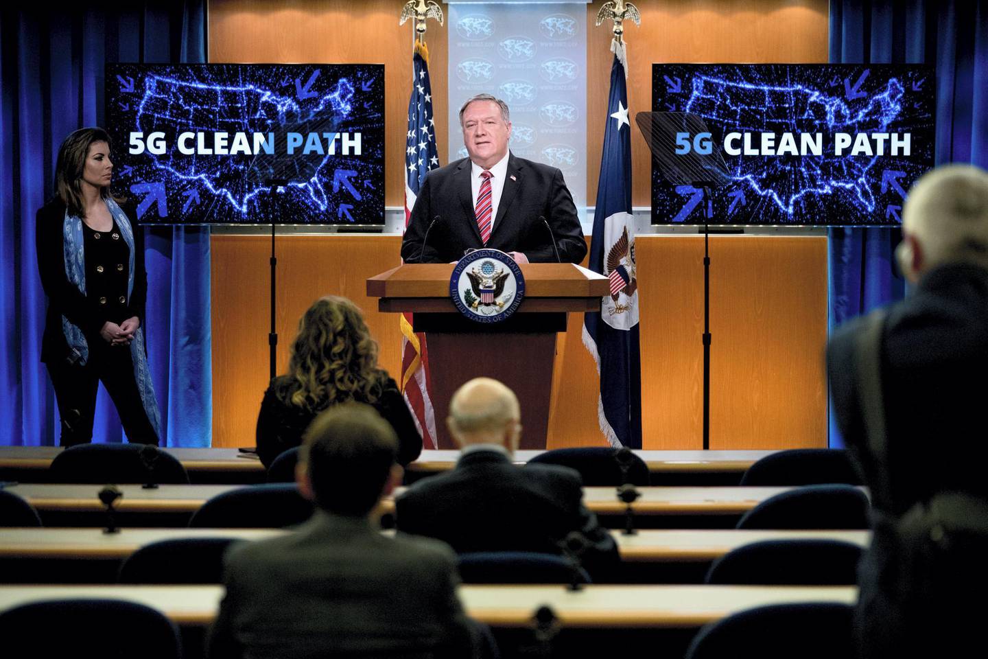 Screens that read “5G Clean Path” with a map of the United States are visible behind Secretary of State Mike Pompeo, accompanied by State Department spokeswoman Morgan Ortagus(L), as he speaks at a news conference at the State Department on April 29, 2020, in Washington,DC. (Photo by Andrew Harnik / POOL / AFP)