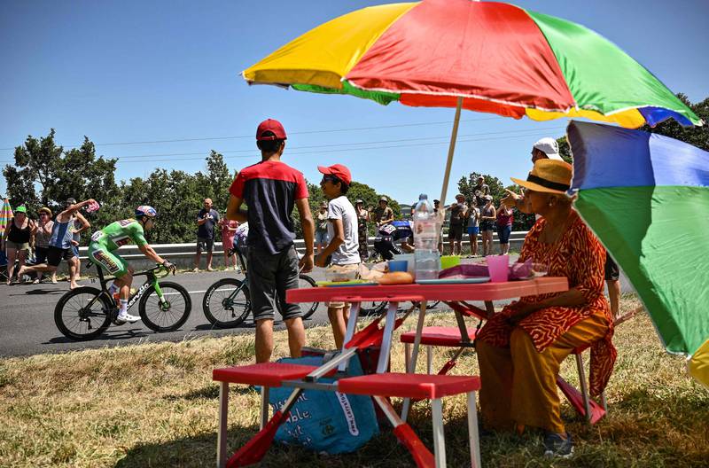 A spectator enjoys a picnic as Jumbo-Visma rider Wout Van Aert, wearing the top sprinter's green jersey during Stage 15. AFP