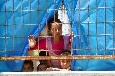 Syrian refugee children look through a fence at a refugee camp. AFP