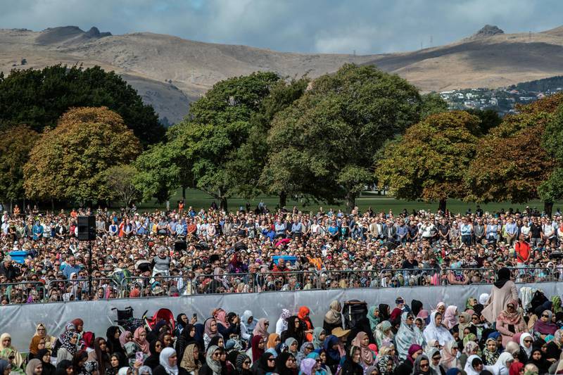 Visitors look on as Muslims attend Friday prayers in a park near Al Noor mosque in Christchurch, New Zealand. 50 people were killed, and dozens were injured in Christchurch on Friday, March 15 when a gunman opened fire at the Al Noor and Linwood mosques. The attack is the worst mass shooting in New Zealand's history. Getty Images
