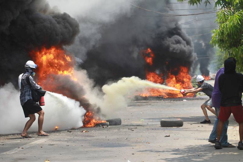 Protesters extinguish fires during a protest in Thaketa township Yangon. AP Photo