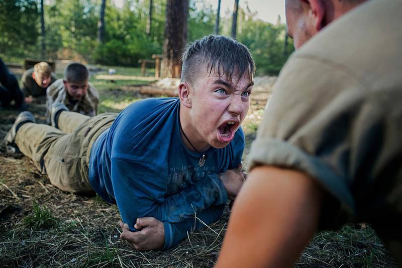 A teenager is emotionally charged by his instructor during tactical training at the Azov battalion's summer camp, near the village of Buzova, 30 kilometres west of Kiev, Ukraine. It is the second summer the Ukrainian volunteer battalion has organised a patriotic camp for children. Photo Alex Masi.