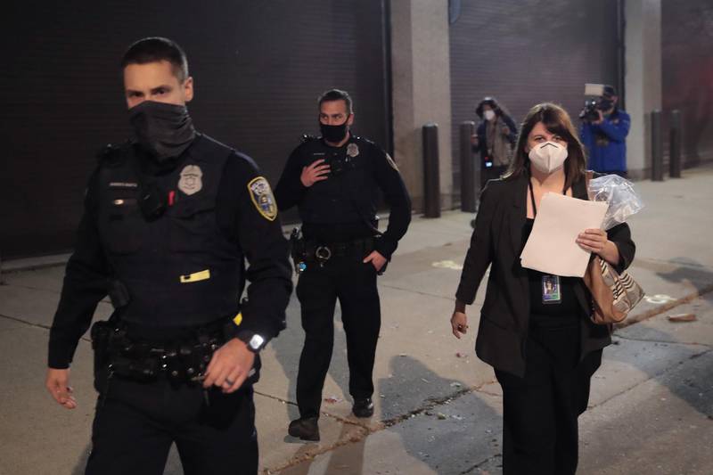 Claire Woodall-Vogg, executive director of the Milwaukee election commission is escorted by police from the central count location where absentee ballots were being counted carrying the final count in Milwaukee, Wisconsin. AFP