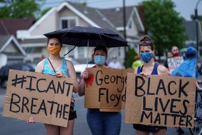 Women hold signs while protesting near the area where a Minneapolis Police Department officer allegedly killed George Floyd, in Minneapolis, Minnesota.  AFP