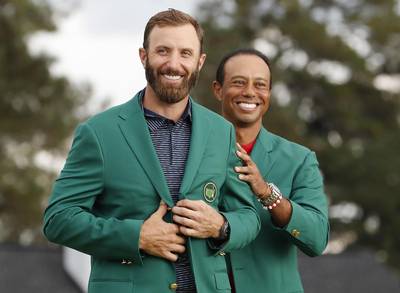 Dustin Johnson of the US is presented his green jacket by defending champion Tiger Woods. EPA