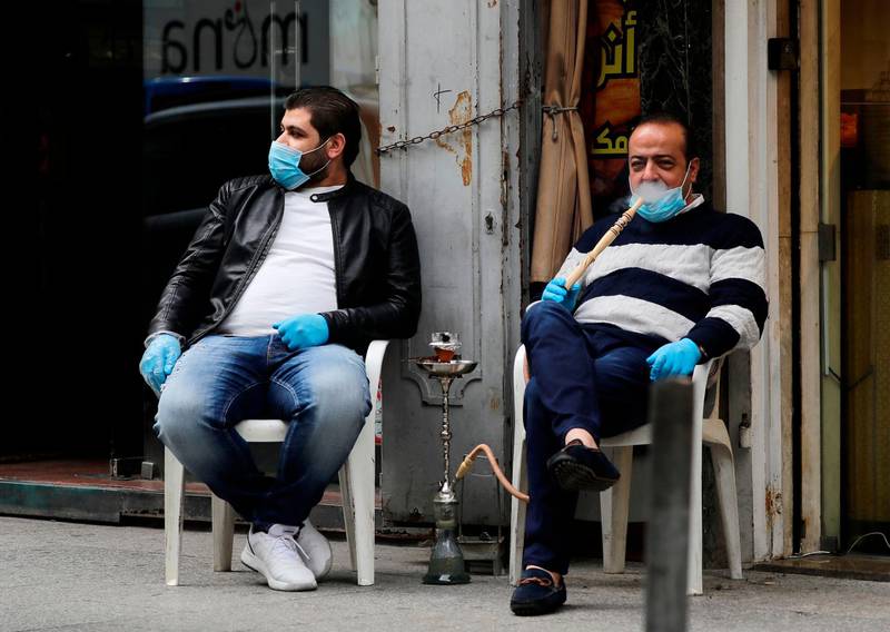 Lebanese men wearing protective masks smoke water pipe or nargileh in Beirut. Lebanon suspended flights from countries hit hardest by the novel coronavirus after announcing its second death from the pandemic in two days. The Mediterranean nation has recorded at least 61 cases of COVID-19. Prime Minister Hassan Diab said Lebanon would suspend all trips to and from Italy, South Korea, Iran and China, the hardest-hit countries. AFP