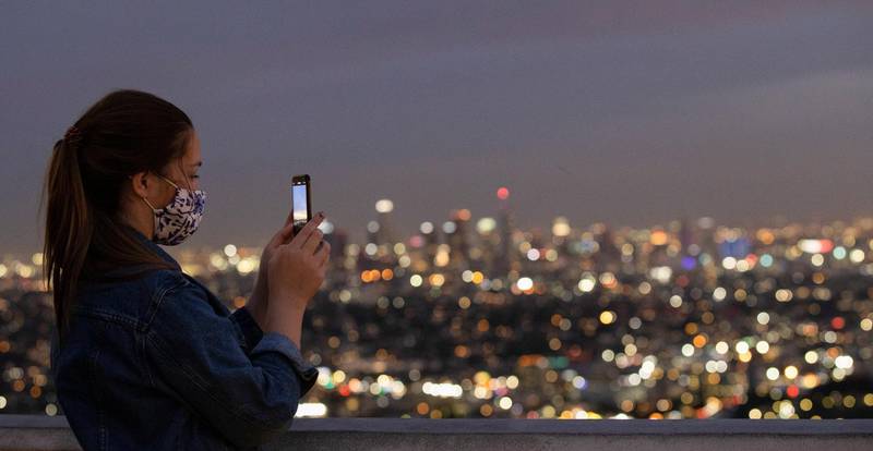 A person uses her mobile phone at sunset from Griffith Observatory during a partial lockdown, in Los Angeles, California. Reuters
