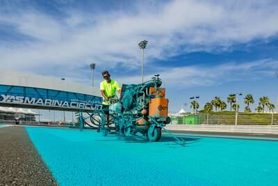 A worker fills in Yas's signature blue trackside decorations