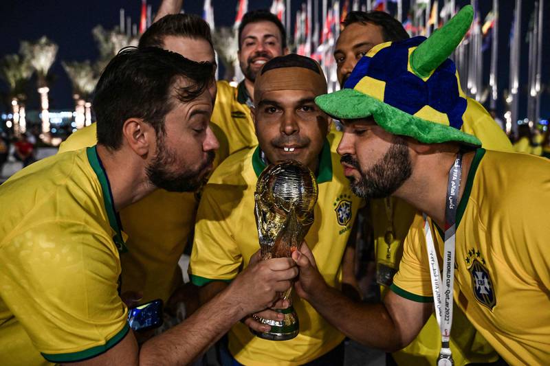 Brazil fans — including a lookalike of Brazilian legend Ronaldo — pose with a replica of the World Cup trophy at Flag Plaza in Doha. AFP