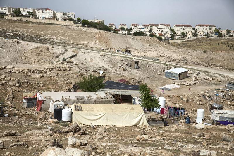 The Jewish settlement of  Kfar Adumim is seen on the hill Congregated metal shanty homes homes A 8 week old baby Beduin baby girl is seen on a mattress in the garden of a home in the tiny West Bank Beduin village of Khan al-Ahmar  on May 2,2018.The Israeli Supreme Court is expected next week to rule on the fate of the village, situated east of Jerusalem between the expanding settlements of Maale Adumim and Kfar Adumim.  The Israeli state says Khan al-Ahmar must be leveled because its structures are situated on state land and were built without permits, which are nearly impossible to obtain in the part of the West Bank known as area C, under full Israeli control.(Photo by Heidi Levine for The National).