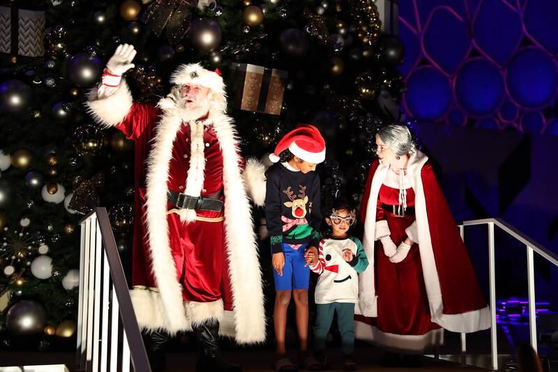 Santa Claus and Mrs Claus with young visitors at Al Wasl Plaza. Pawan Singh / The National